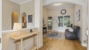 A living room with a fireplace, a sofa, a coffee table, and a dining area in the background.
