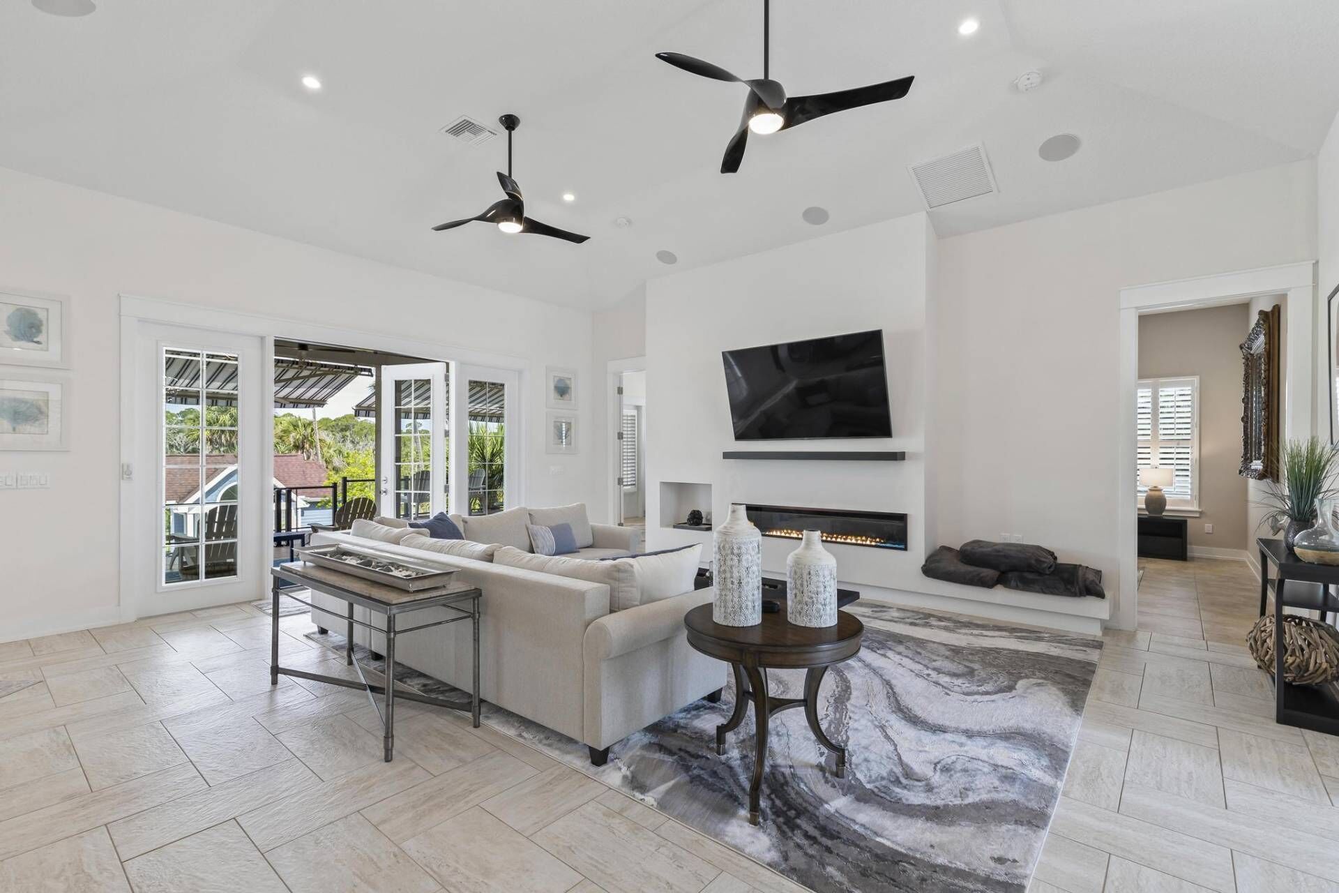 A spacious living room with a fireplace, ceiling fans, and a large TV.