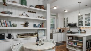 A kitchen with white cabinetry, wooden flooring, and a dining area with a white table and chairs.