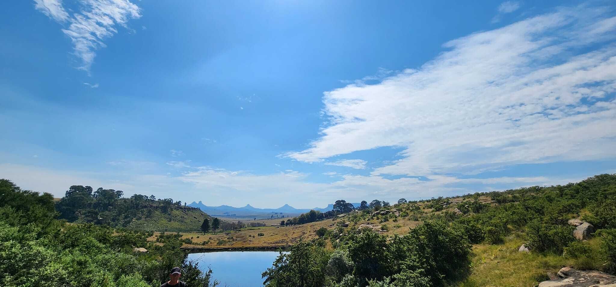 Eine natürliche Landschaft mit einem See, Hügeln und Bäumen.