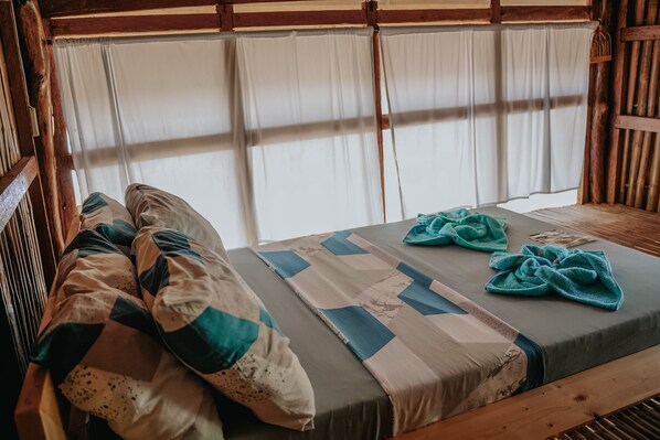 A bed with a quilt, pillows, and two towels.