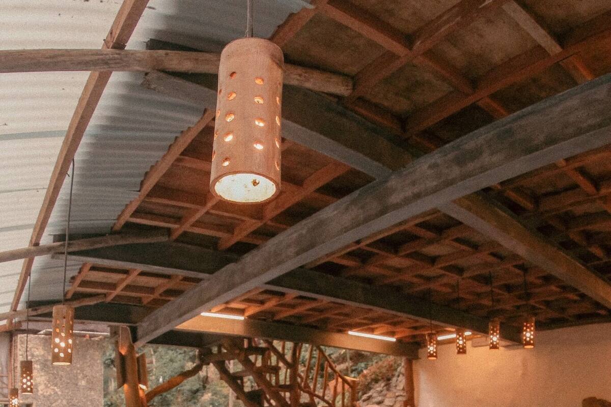 Een houten terras met een zwembad, een houten trap en hangende lampen.