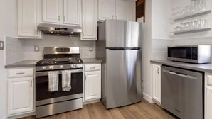 A modern kitchen with white cabinetry, stainless steel appliances including a refrigerator, stove, oven, and dishwasher, and a microwave on the countertop. - Pacifica Storybook Beach House, 2 blocks from beach, pier and golf, 10 min to SF (Pacifica)