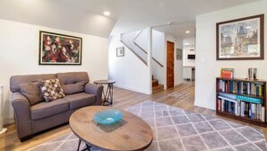 A living room with a sofa, coffee table, and bookshelf. - Pacifica Storybook Beach House, 2 blocks from beach, pier and golf, 10 min to SF (Pacifica)
