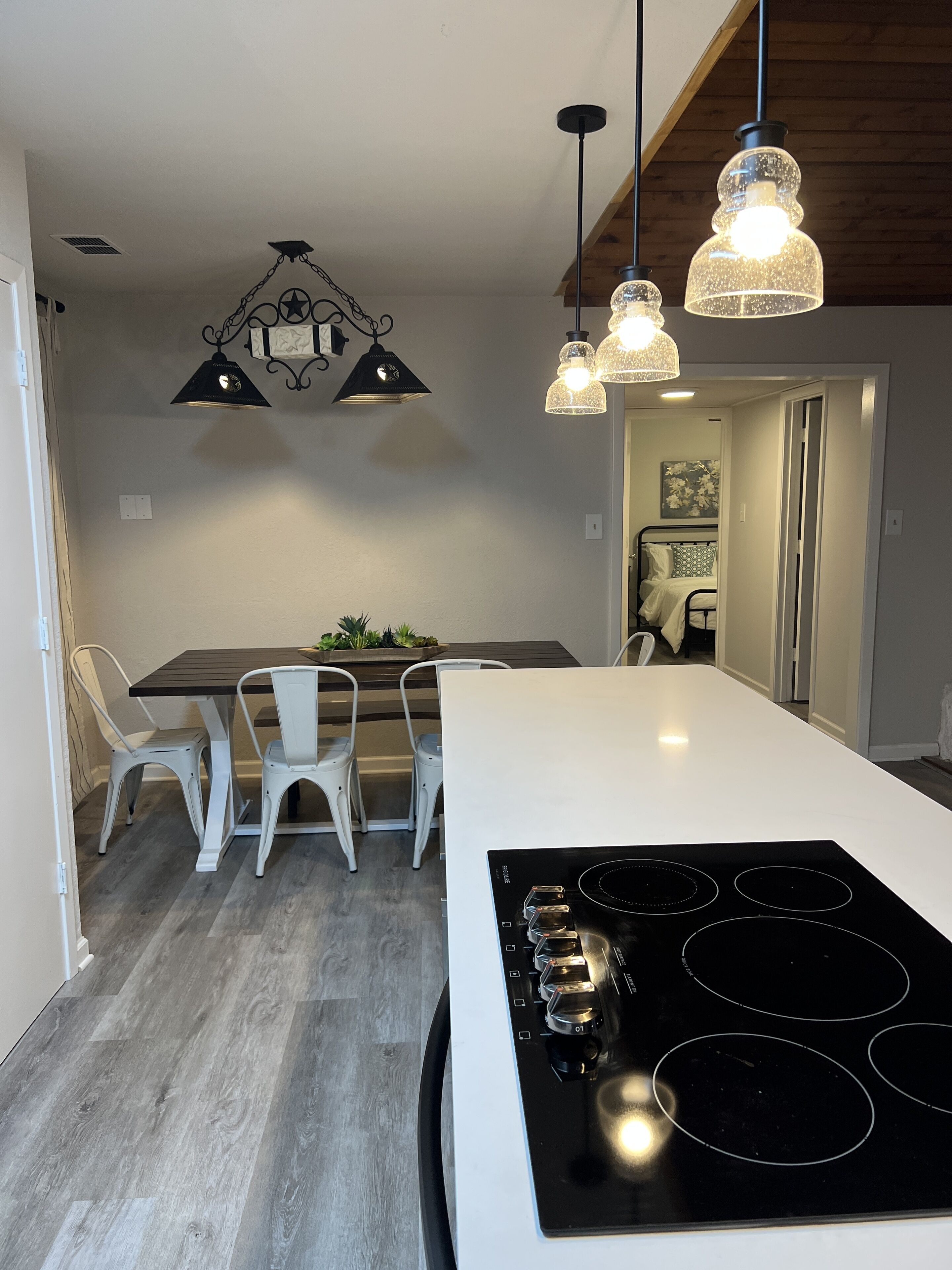 Een moderne keuken met een wit kookeiland, een zwart inductiefornuis en hanglampen.