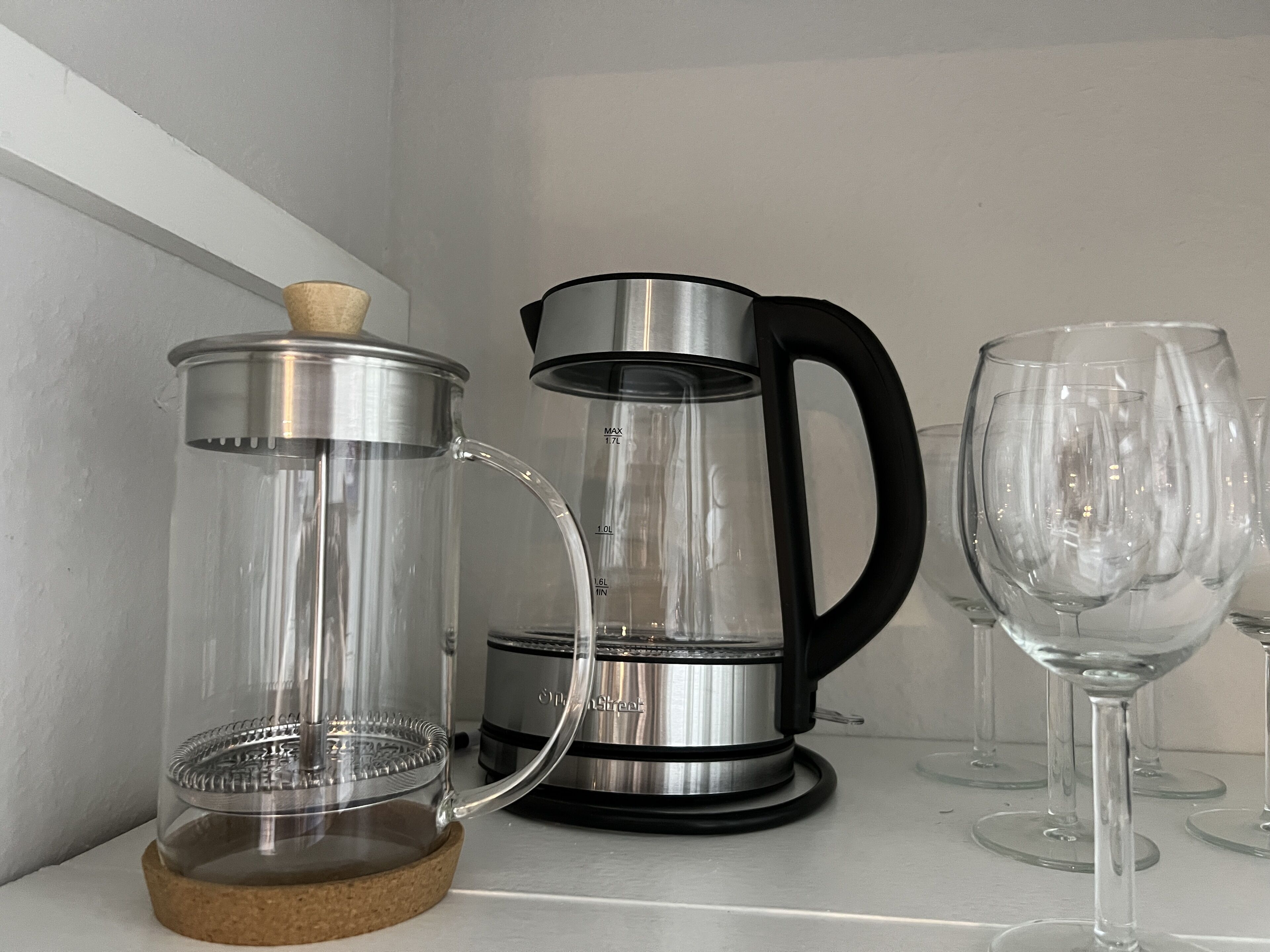 A kitchen with a coffee maker and a glass carafe on a countertop.