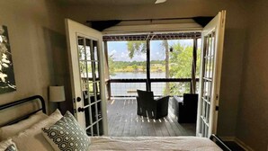 Ein Schlafzimmer mit einem großen Bett, Blick auf eine Terrasse und einem Sessel.