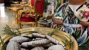 Une figurine décorative en céramique, représentant un personnage tenant une théière, une assiette de biscuits et un petit brûle-parfum, dans une pièce meublée avec goût et ornée d’un lustre.