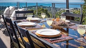 A table set for four with a clear view of the ocean and mountains in the background.
