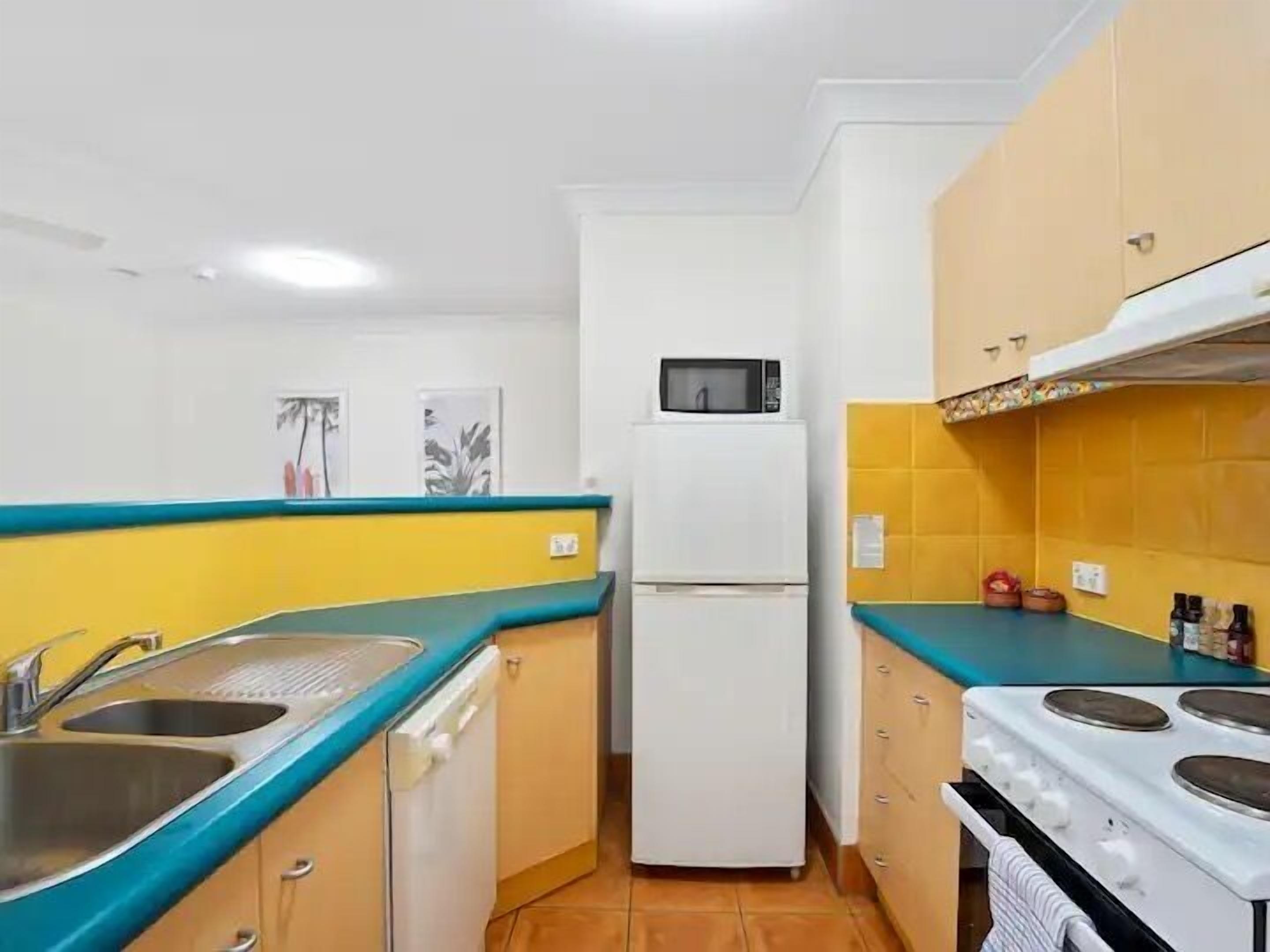 Cocina compacta con pileta, microondas, refrigerador, estufa y alacenas.
