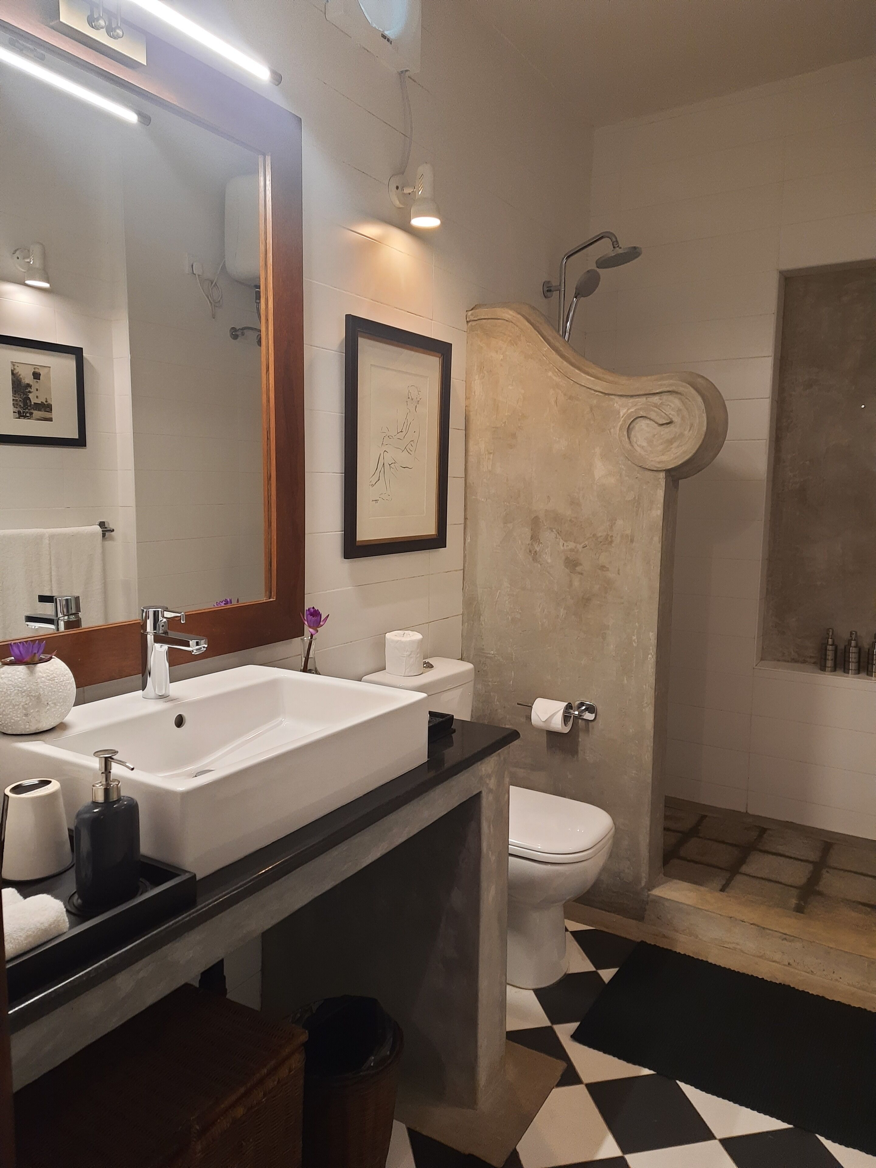 A modern bathroom with a large mirror, two sinks, a toilet, and a shower.