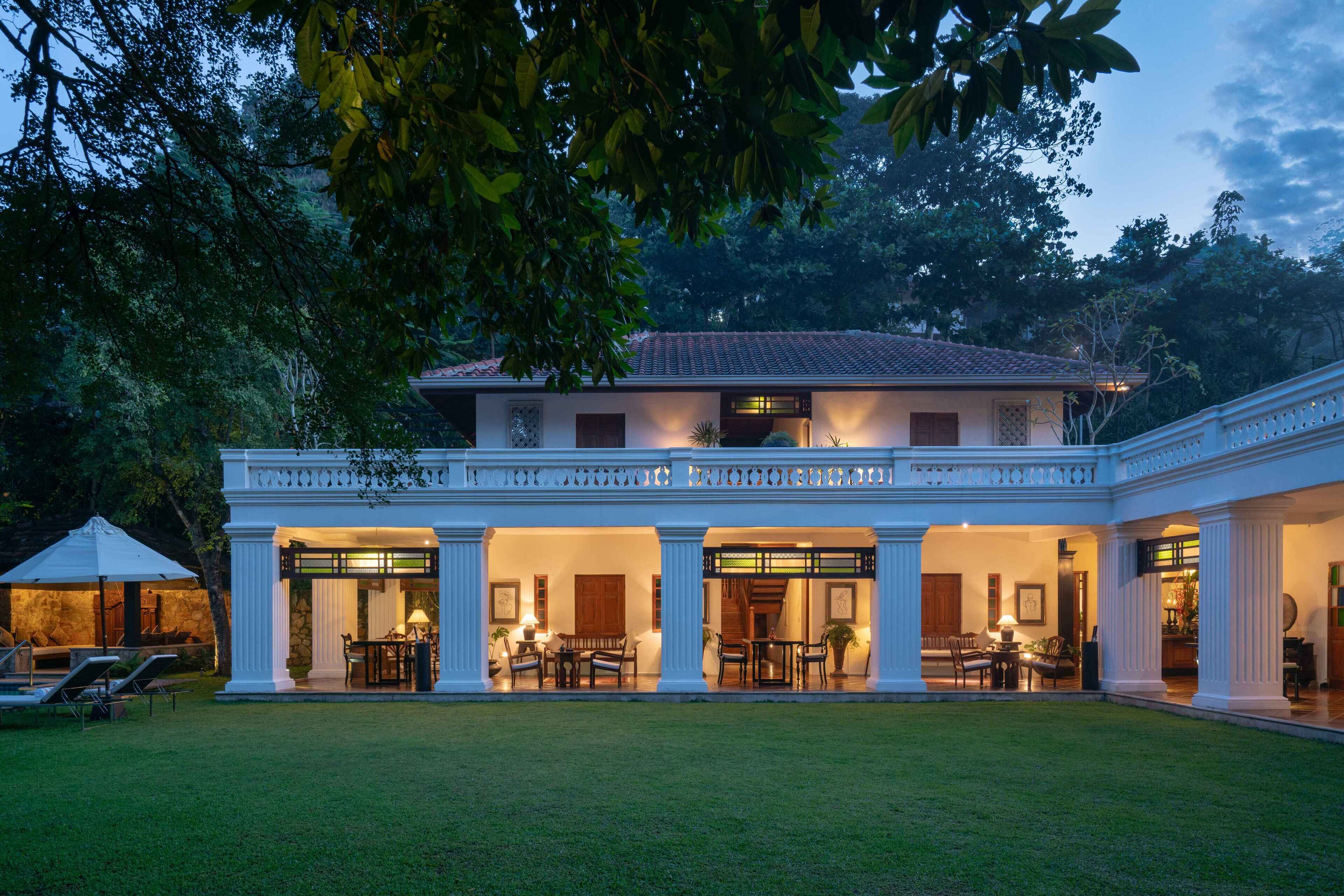 A two-story building with a covered patio area, columns, and outdoor seating.