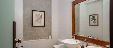 A modern bathroom with two sinks, a toilet, and a framed artwork on the wall.