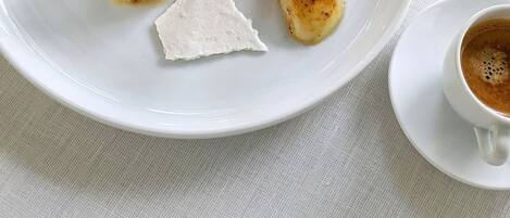 A plate with a dessert, a spoon, and a cup of coffee on a table.