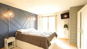 Ein Schlafzimmer mit Bett, Nachttischen, einem Fernseher und einem Fenster.