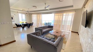 A spacious living area with a grey sofa, a coffee table, and a dining area with chairs and a table.