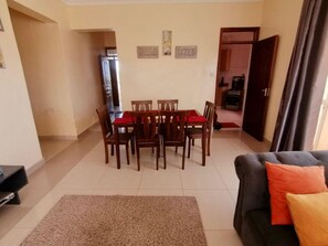A dining area with a table and chairs, a sofa, and a rug. - Nyali Mall Apartments by CHH (Mombasa)