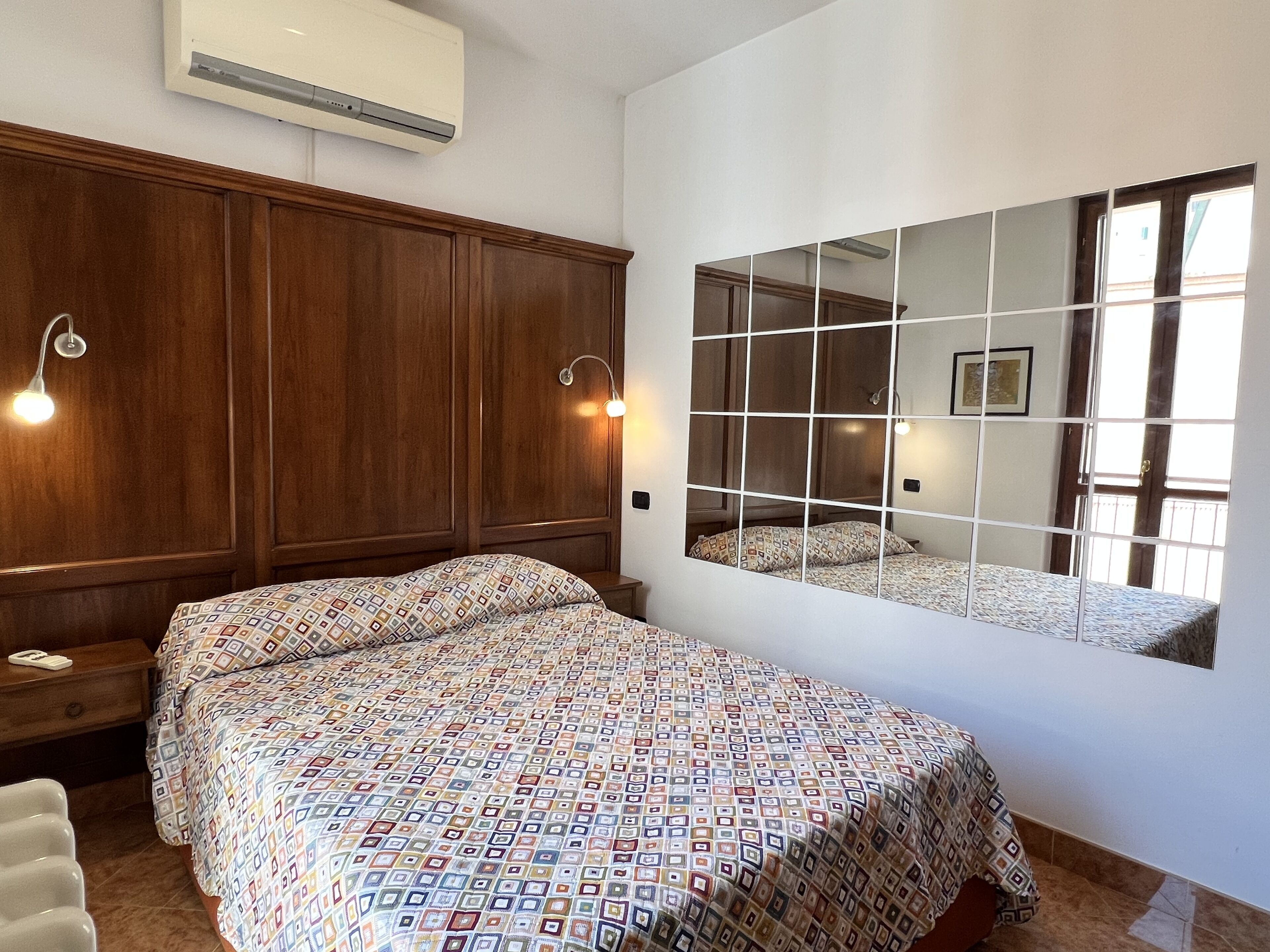 Ein Schlafzimmer mit einem großen Bett, einem Holfischschrank und einem an der Wand befestigten Spiegel.