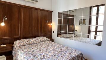 Ein Schlafzimmer mit einem großen Bett, einem Holfischschrank und einem an der Wand befestigten Spiegel.