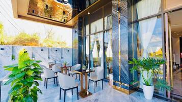 A modern indoor space with marble flooring, seating areas, and large windows.