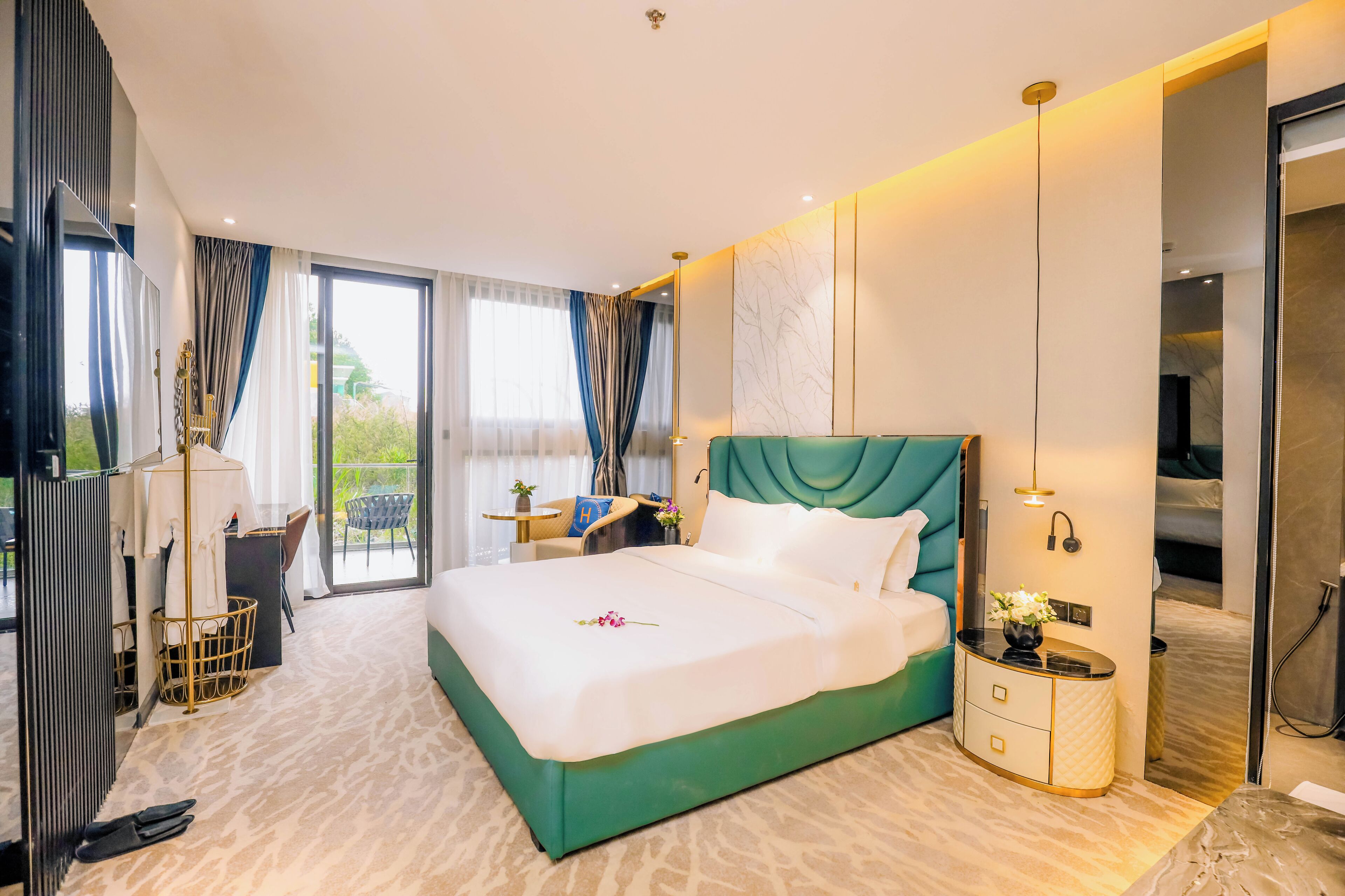A modern hotel room with a large bed, a small desk, a chair, and a view of the outdoors.