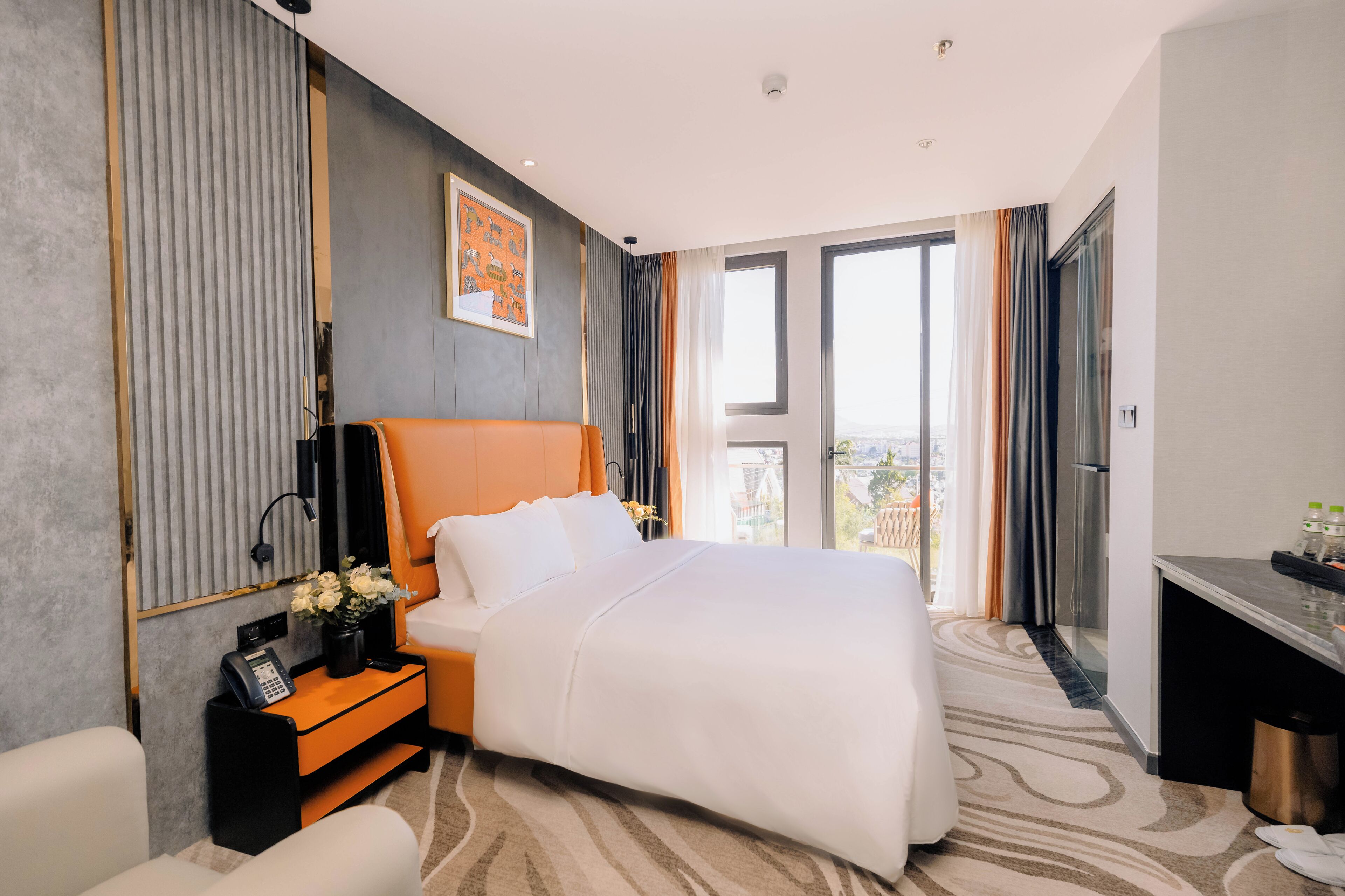 A hotel room with a bed, a desk, a phone, and a window with curtains.