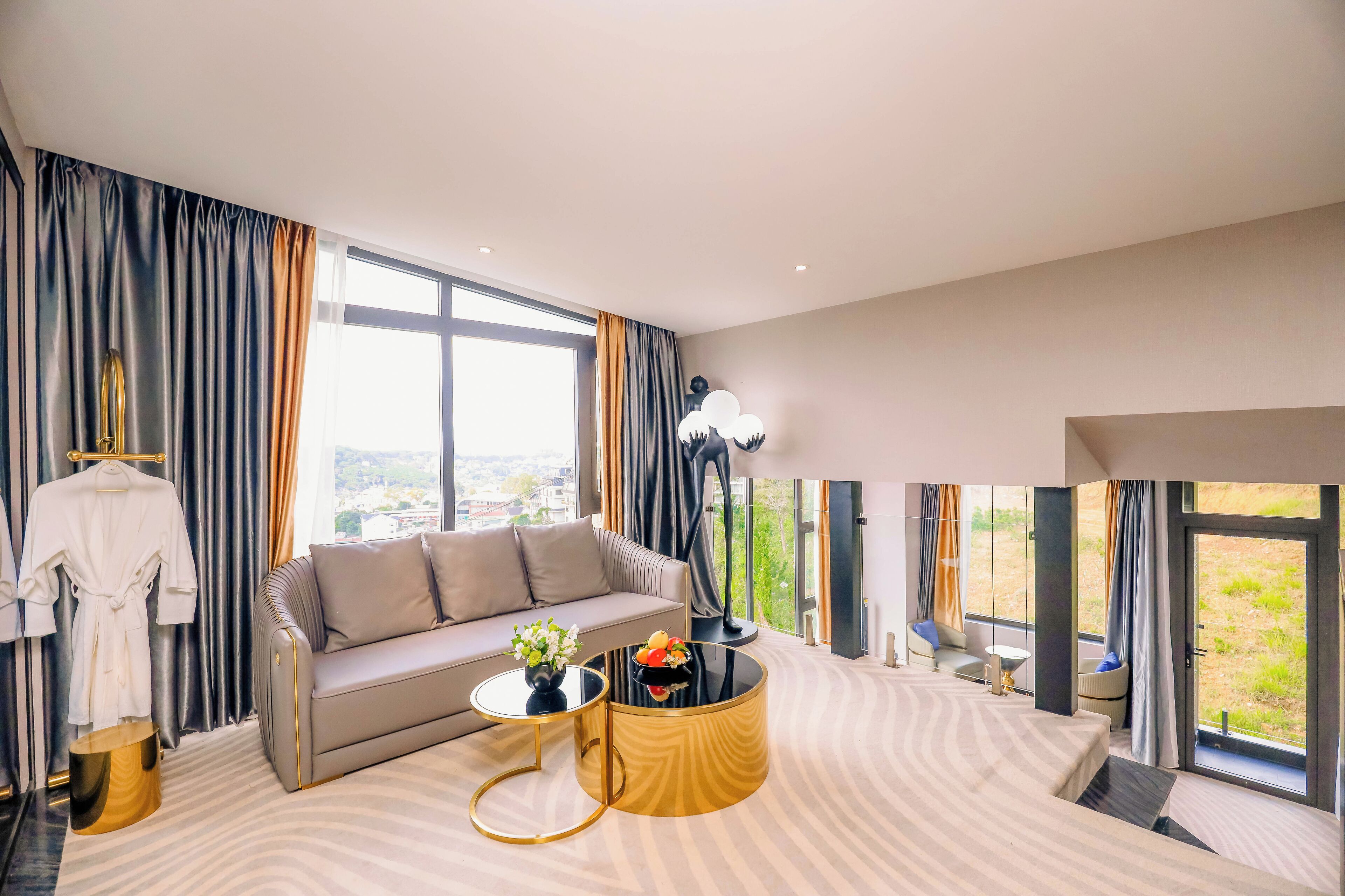 Ein modernes Hotelzimmer mit einer Couch, einem runden Couchtisch und Blick ins Freie.