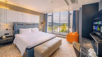 A modern hotel room with a large bed, a desk with a computer, and a view of the city.