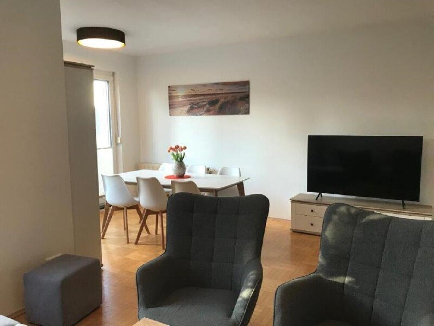 Un salon moderne comprenant un coin repas, un téléviseur à écran plat et un tableau accroché au mur.