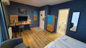 Habitación de hotel con cama, escritorio, silla, armario y puerta de baño.
