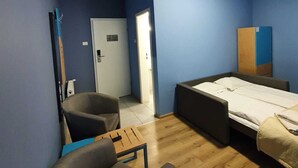 Una habitación con paredes azules, una cama, una silla, un escritorio y una puerta.