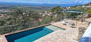 A rooftop pool with a stone deck and a glass railing, overlooking a scenic landscape with houses and trees. - Luxurious apartment with private pool (Rosas / Roses)
