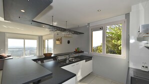 Una cocina moderna con una isla grande, horno empotrado y ventana con vistas al exterior.