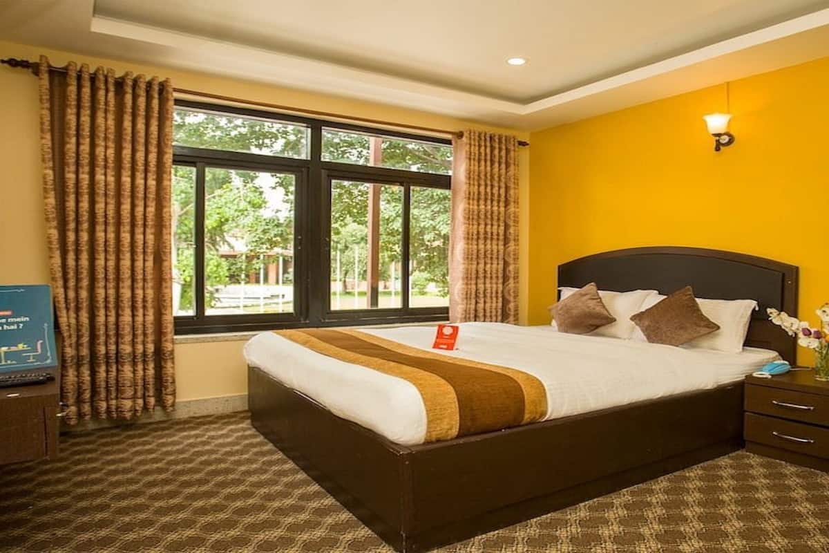 Een hotelkamer met een groot bed, een garderobe, een nachtkastje met een lamp en een raam met gordijnen.