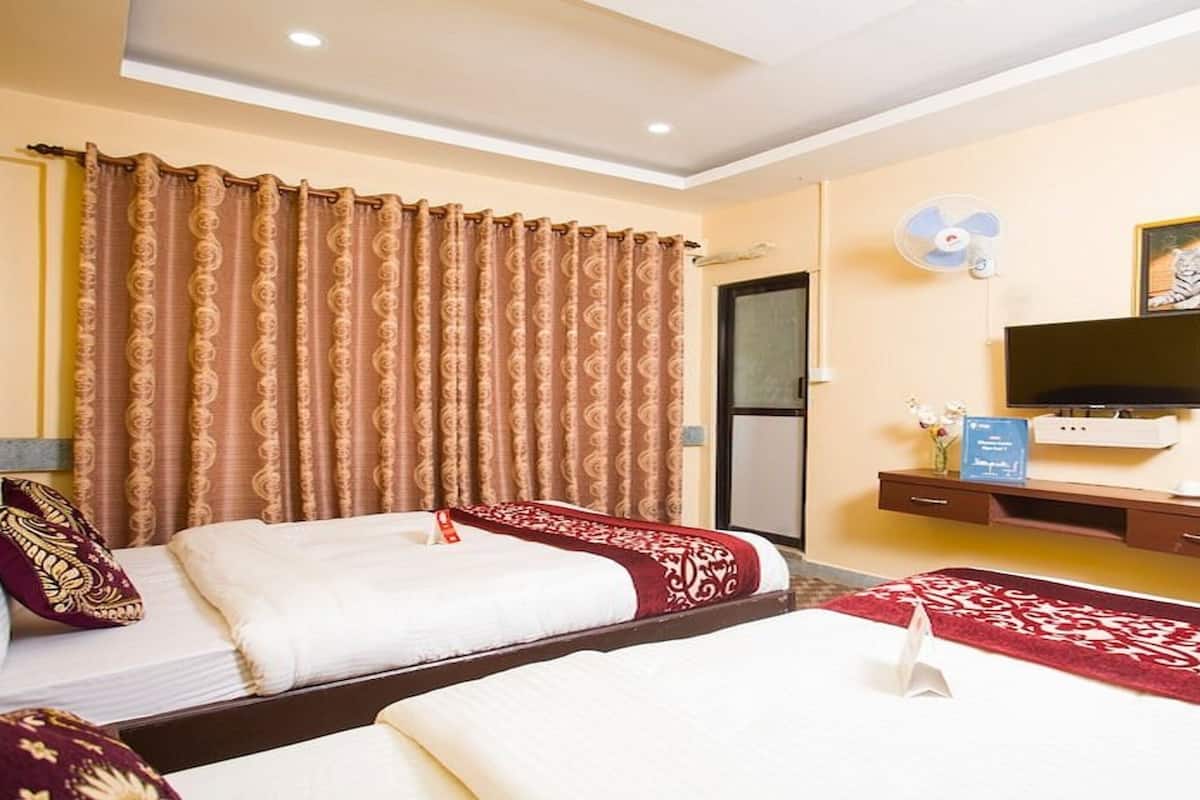 Een hotelkamer met twee bedden, een televisie, een ventilator en een schilderij aan de muur.
