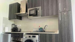 Une cuisine compacte équipée d’un four à micro-ondes, d’un four et d’un lave-linge intégrés.