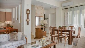 Ein Wohnzimmer mit einer Couch, einem Couchtisch, einem Esstisch mit Stühlen, einer Uhr und einem Kamin.