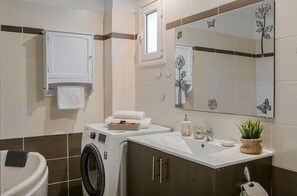 Ein modernes Badezimmer mit Waschmaschine, Waschbecken und einem spiegel mit floralen Mustern.