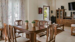 Ein Essbereich mit Holztisch und -stühlen, einem Schrank mit Lautsprechern und einem Fernseher an der Wand.