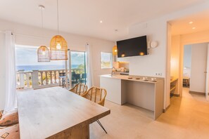 Una cucina moderna con TV, zona pranzo con sedie e un balcone con vista.