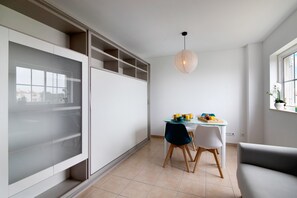 A modern kitchen with a dining area, a built-in cabinet, and a pendant light.