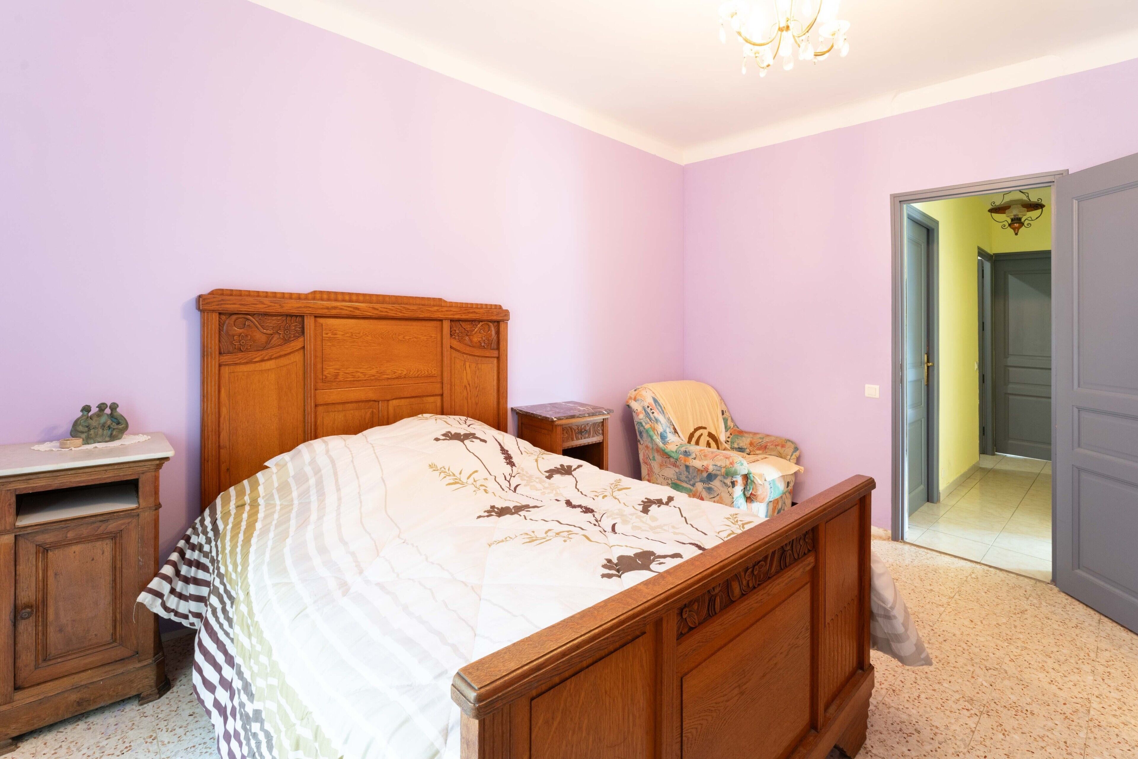 A bedroom with a wooden bed, a nightstand, a chair, and a dresser.