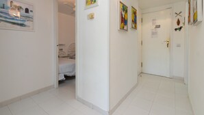 A hallway with a bed, a door, and artwork on the walls. - Apartment 'Les Magnolies' with Sea Views, Wi-Fi and Air Conditioning (PLAYA  DE  ARO)