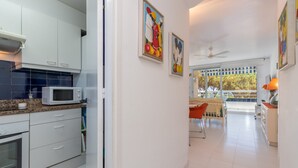 A modern kitchen with white cabinets, a microwave, and a dining area with a table and chairs. - Apartment 'Les Magnolies' with Sea Views, Wi-Fi and Air Conditioning (PLAYA  DE  ARO)