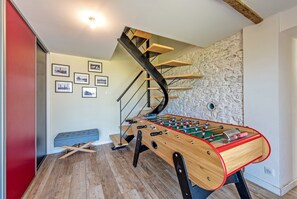 A room with a foosball table, a bench, a staircase, and framed pictures on the wall. - Holiday Home 'Villa Léonie – Indoor Pool' with Terrace, Garden, and Wi-Fi (Kerlouan)