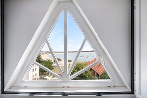 A triangular skylight window with a view of a beach and buildings.