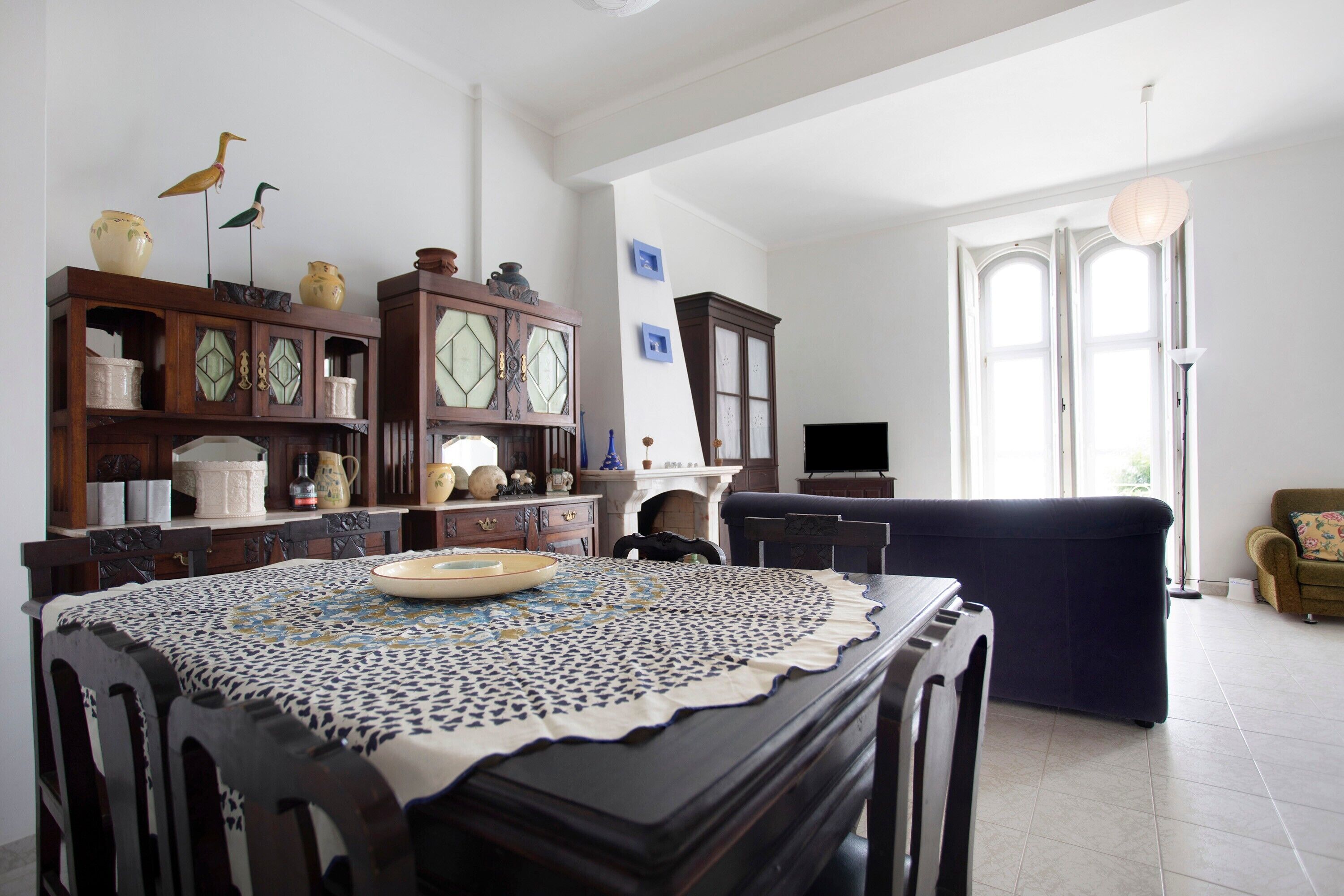A living room with a dining table, chairs, a sofa, and a television.