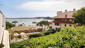 A coastal hotel with a view of the sea, a garden area, and a row of wooden bungalows. - Apartment 'Vista Baia' with Sea View, Shared Pool and Wi-Fi (São Martinho do Porto)