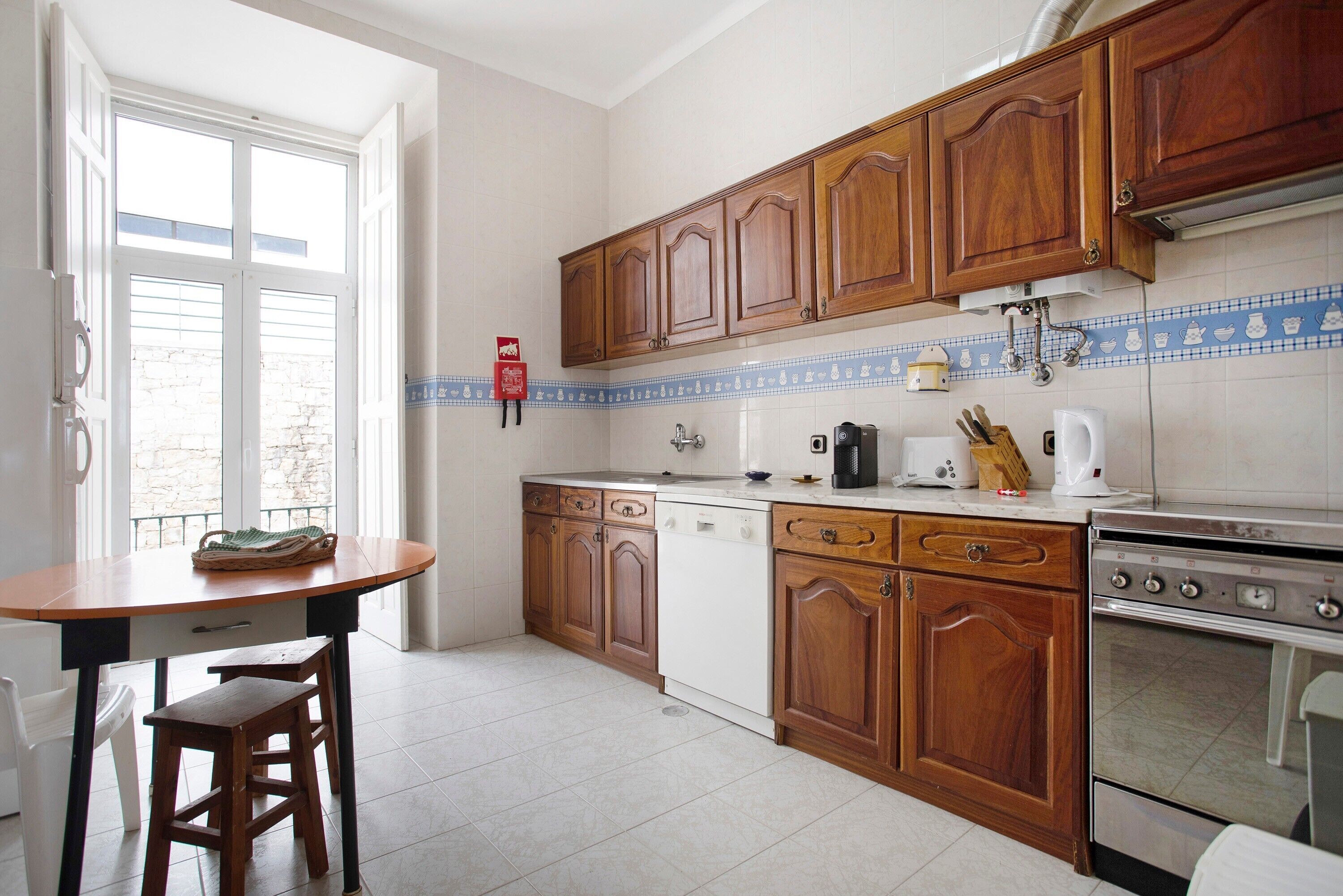 Eine Küche mit Holzausstattung, einem Geschirrspüler, einem Backofen und einem Esstisch mit Stühlen.