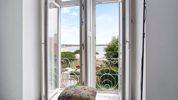 A room with a large window, a chair with floral upholstery, and a floor lamp. - Apartment 'Vista Baia' with Sea View, Shared Pool and Wi-Fi (São Martinho do Porto)